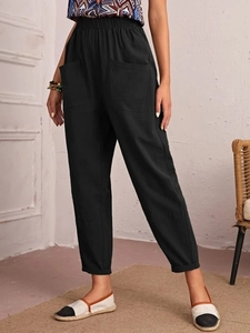 Detail of black cotton linen pants with elastic waist and side patch pocket design