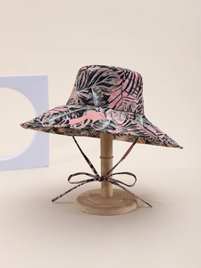 Detail of pink tropical leaf print sun hat with adjustable chin strap on wooden stand