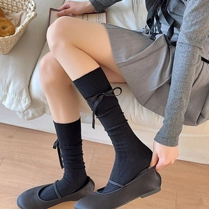 Detail view of black calf socks with vertical stripes and delicate silk ribbon bows
