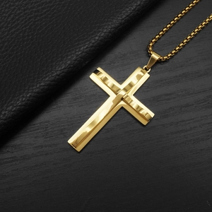 Detailed view of a gold layered cross pendant with a woven chain on black texture