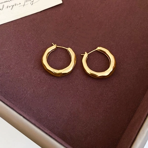 Detail view of 18K gold plated hoop earrings with textured finish on velvet tray