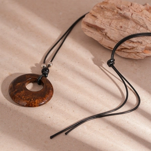 Vintage resin hollow circle long pendant necklace with brown amber-like texture on beige background