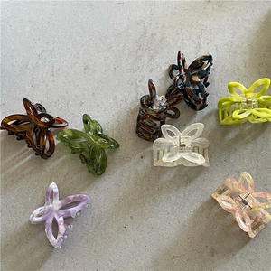 Flat lay of small acetate hollow butterfly hair claws in various marble and solid colors