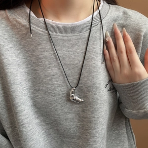 Detail of silver crescent croissant pendant with pleated texture on a black cord