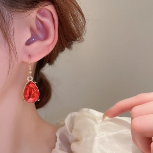 Close-up of red teardrop faceted earrings with gold hooks on a fashion model