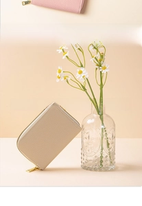 Detail of beige litchi grain leather card bag with gold zipper and RFID protection