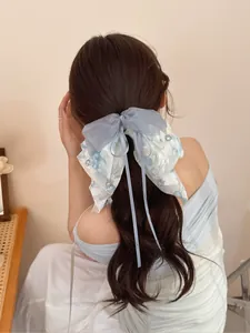 Detail of light blue ribbon bow hair claw clip with floral pattern and crystal beads