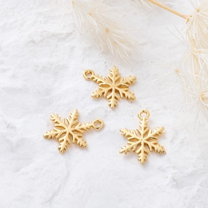 Detailed close-up of three 18K gold-plated snowflake charms for DIY jewelry making