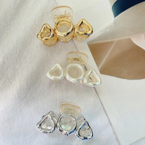 Close-up of geometric hair claws in gold, silver and pearl white with chain link texture