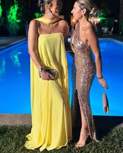 Femmes en robe maxi jaune en soie et robe de soirée dorée à paillettes avec fente près de la piscine