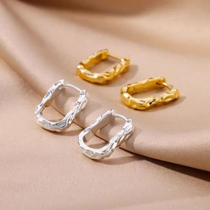 Detail of gold and silver irregular hammered rectangular hoop earrings on satin