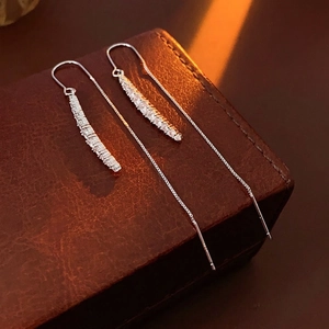 Orecchini a catena d'argento con nappe e zirconi su una superficie in pelle marrone