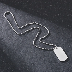 Close-up of polished silver steel dog tag pendant with beaded chain on black background