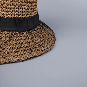 Detail view of woven sun hat featuring a black lace ribbon bow and polka dot mesh veil