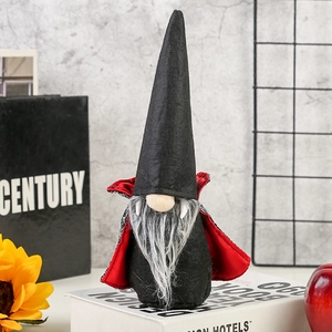 Detail of Halloween vampire gnome with black pointed hat, red cape, and fangs on a desk