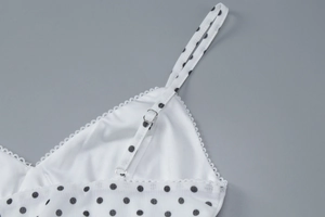 Detail of white polka dot fabric featuring lace trim and adjustable thin shoulder straps