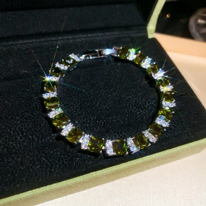 Close-up of a green emerald bracelet with square-cut stone on black velvet