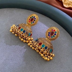 Dettaglio macro di orecchini Jhumka vintage con smalto colorato e nappe di perline