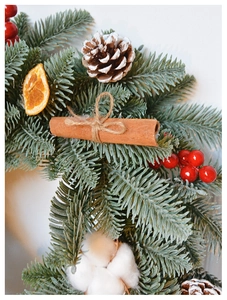 Detailed close-up of Christmas wreath with pine needles, red berries, and cinnamon sticks