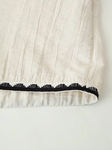 Close-up of beige linen fabric texture with black geometric wave embroidery detail