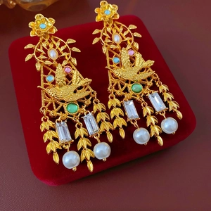 Primer plano de pendientes vintage dorados con gemas coloridas y perlas colgantes