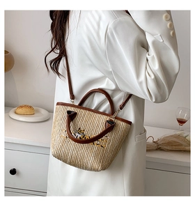 Detail of woven straw basket bag with tiger embroidery and brown PU leather strap