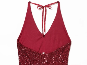 Close-up of red sequined halter dress neck detail with satin ribbon ties on white background