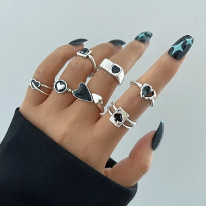 Close-up of 6 silver gothic rings with heart and spade motifs on hand with black nails