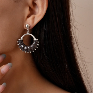 Close-up of vintage geometric hoop earrings with black leather and silver bead detail
