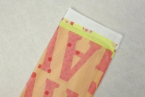 Close-up of geometric print mesh fabric showing orange and pink patterns with stitching