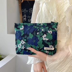 Detail of floral jacquard makeup bag in deep blue with elegant woven leaf patterns