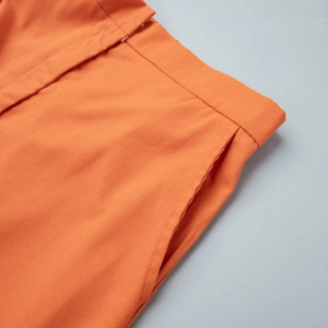 Detail of orange cotton skirt set featuring side pockets and textured fabric waist