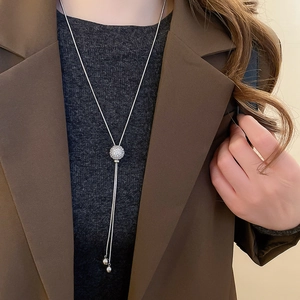 Detail of silver long tassel necklace with a sparkling pavé zircon sphere pendant