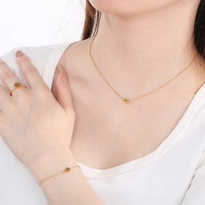 Golden clover jewelry set including necklace, bracelet and ring worn by a model
