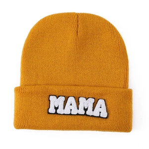 Close-up of bright yellow knitted beanie featuring white MAMA towel embroidery