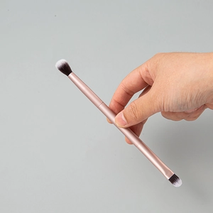 Dual-ended champagne gold makeup brush with black and white gradient bristles for blending