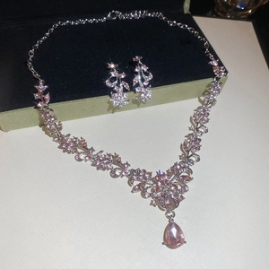 Close-up of sparkling silver leaf necklace and earrings set with pink teardrop gems
