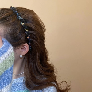 Close-up of a colorful woven knit headband worn with elegant pearl jewelry details
