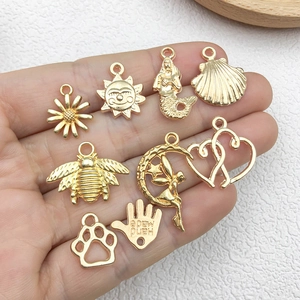 Golden alloy DIY charms set featuring sun, mermaid, and bee shapes held in hand