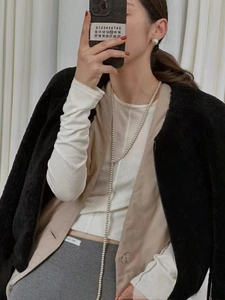 Gros plan d'un long collier de perles superposé porté sur un pull multicolore chic