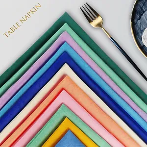 Polyester table napkins in various colors on a marble plate with gold fork for hotel use