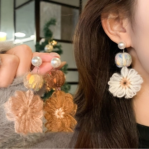 Detailed view of handmade knitted flower earrings with pearls in multiple colors
