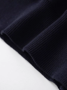 Macro view of ribbed cuffs and hem texture on a dark navy blue striped knit polo shirt