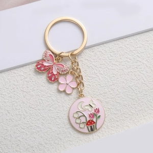 Detailed macro of pink enamel butterfly and flower charms on a golden metal keychain