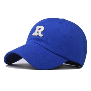 Close-up of white 3D embroidered R letter on deep blue cotton baseball cap surface