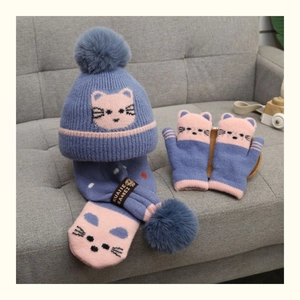 Detailed view of kids winter knit set with hat, scarf and mittens on a grey fabric sofa