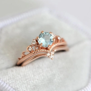 Macro view of rose gold crown ring with light blue round zircon and nested V-shaped band