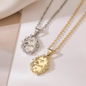 Elegant gold and silver geometric LOVE pendant necklaces on soft fabric background