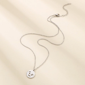Detailed close-up of a silver stainless steel smiley face pendant on a thin link chain