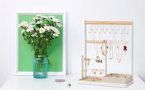 Detail of white iron jewelry rack with wooden bar, earring holes and base tray